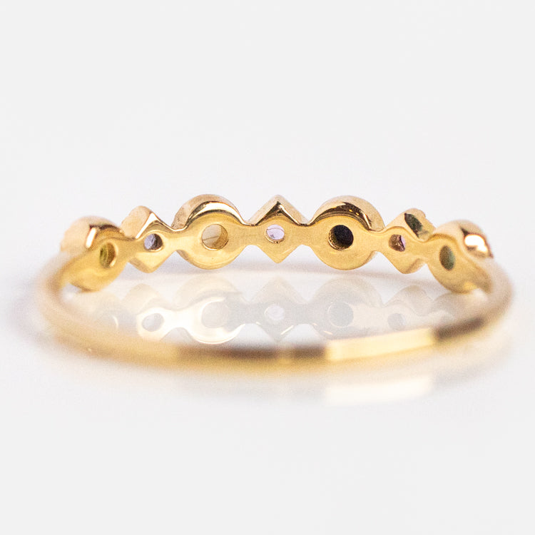 The Solid Gold Balance Acrostic Ring Sample Size 7 is a 9k yellow gold band with a repeating geometric design of small circles, dots, and triangles, shown photographed on a white background.
