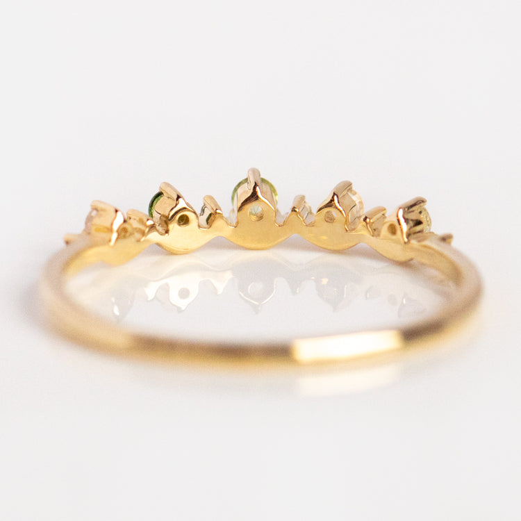 The Solid Gold Amour Acrostic Ring Sample Size 7 is a 9k yellow gold ring with a wavy crown-like design, adorned with small moonstones along the top, shown on a white background.