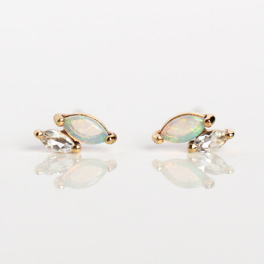 Solid Gold Opal and White Topaz Marquise Studs: marquise-shaped opal earrings set in solid gold, each accented with a clear, teardrop white topaz, shown on a white reflective surface.
