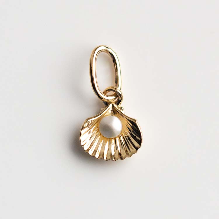 The Solid Gold Nature Charm is a seashell-shaped pendant with a small white pearl at its center, featured on a plain white background.