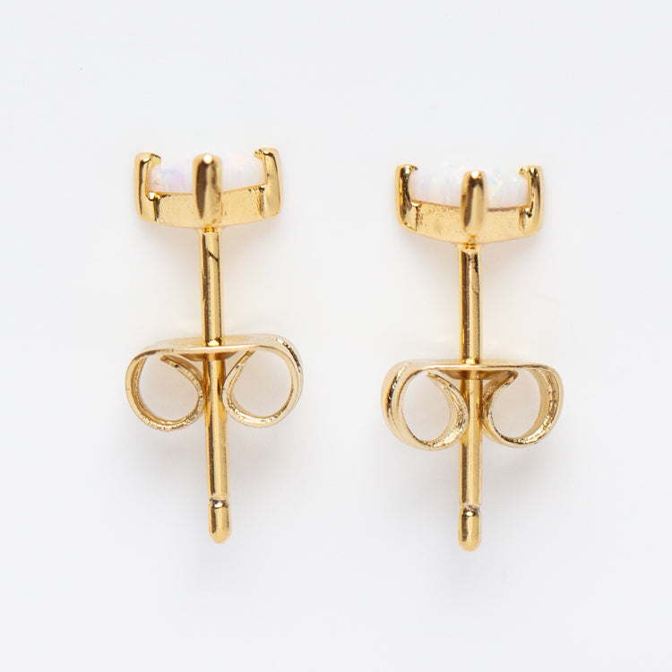 The Iridescent Opal Triangle Studs are 14k yellow gold plated earrings featuring simulated opal stones in four-prong settings, shown on a white background.