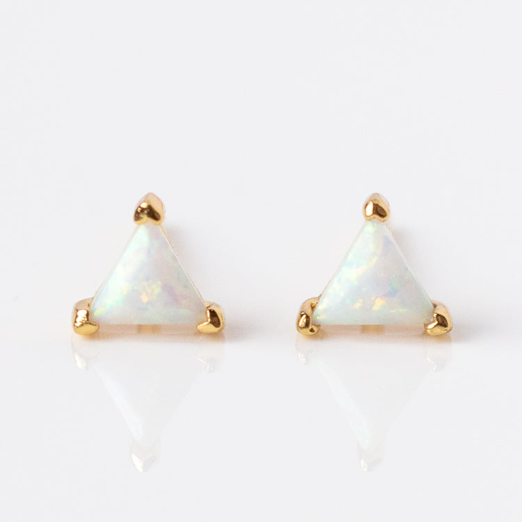 The Iridescent Opal Triangle Studs feature triangular simulated opals in 14k yellow gold plated prong settings, shown against a white background.