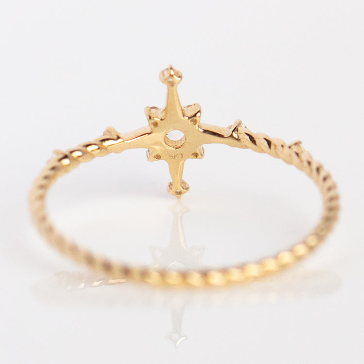 The Solid Gold True North White Sapphire Ring Size 7 Sample features a twisted yellow gold band and a star-shaped setting for a white sapphire, shown from the back against a white background.
