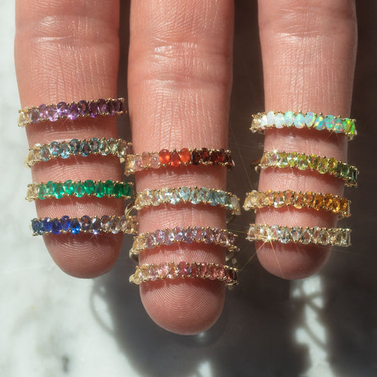 solid gold birthstone rings on a hand for every month