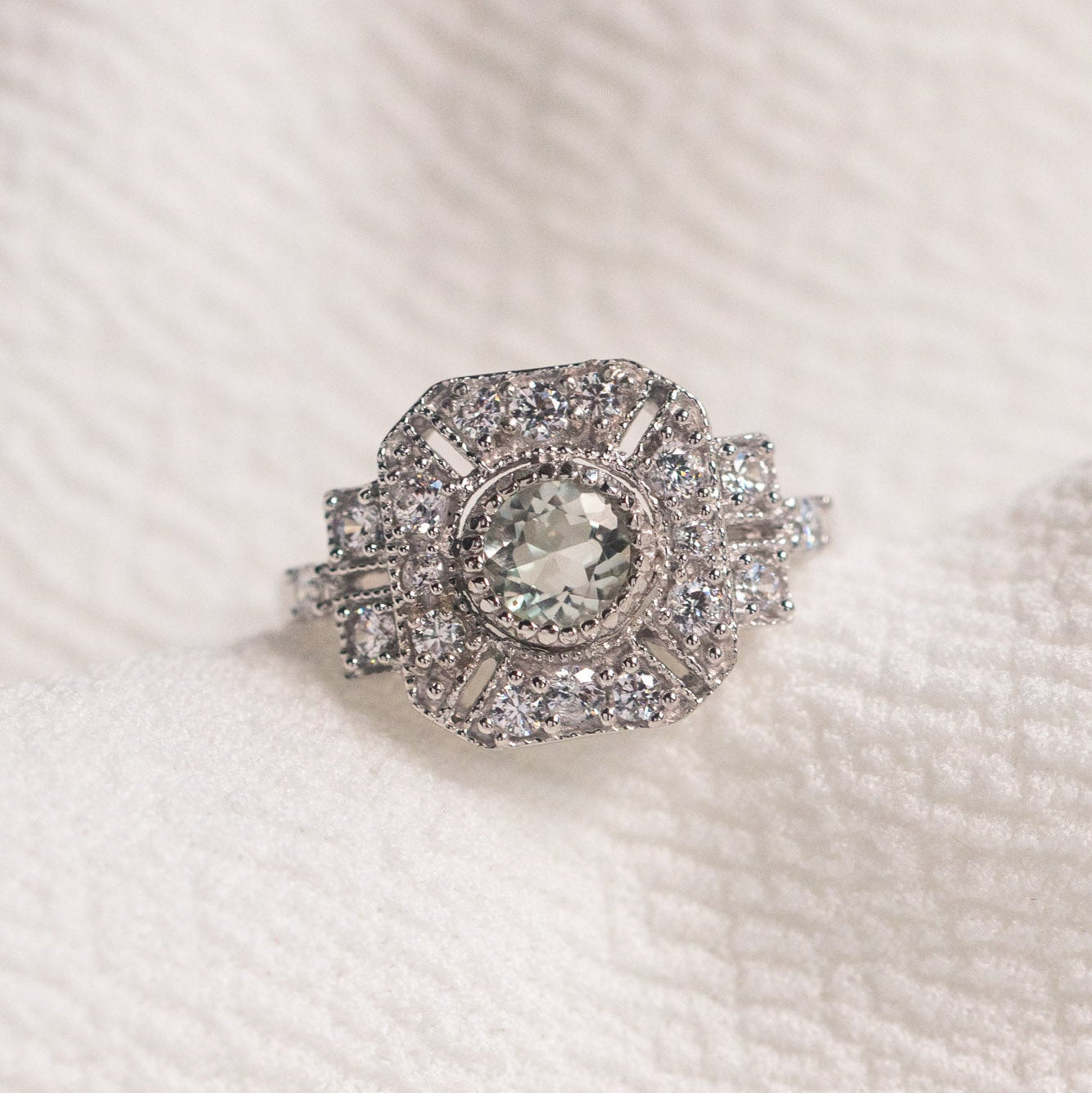Silver ring with a central gemstone on a textured white background