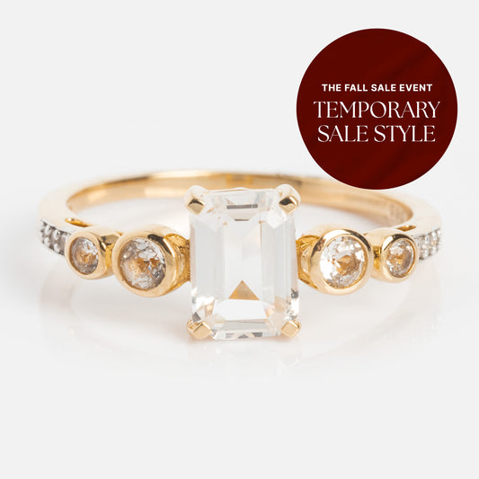 The 14k Vintage Inspired Majesty Ring showcases a large rectangular clear gemstone with three round diamonds on each side, ideal for engagements. A red circular label reads: The Fall Sale Event. Temporary Sale Style.