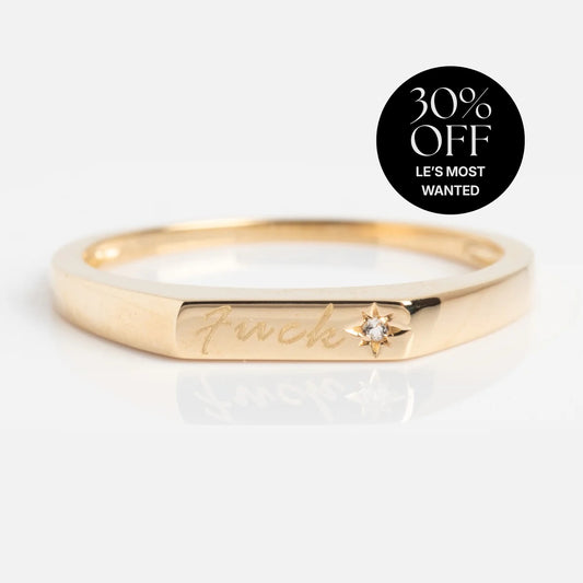 Tiny Fuck Ring: a gold, stackable ring engraved with "fuck," featuring a star-shaped stone. A circular label in the corner says 30% OFF LES MOST WANTED in white text on a black background.