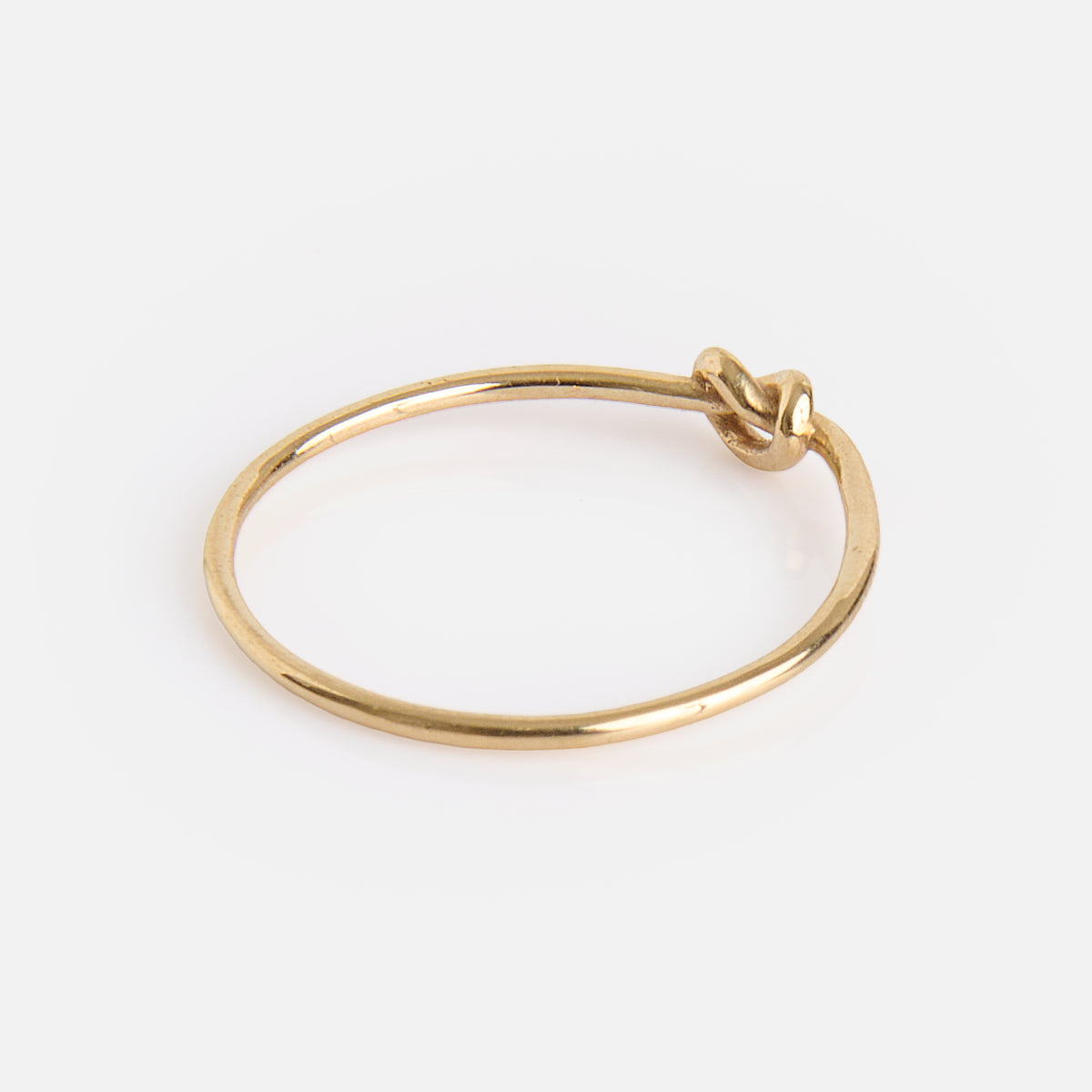 The Solid Gold Simple Knot Ring features a minimalist design with a small knot detail, reminiscent of a simple gold bangle bracelet, and is displayed on a plain white background.