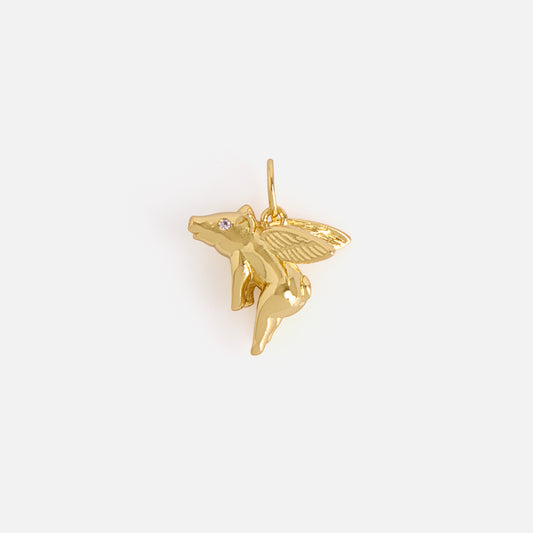 A small, shiny gold “Charms by Mod and Jo” pendant shaped like a flying pig with detailed wings and a tiny gemstone eye, photographed against a plain white background.