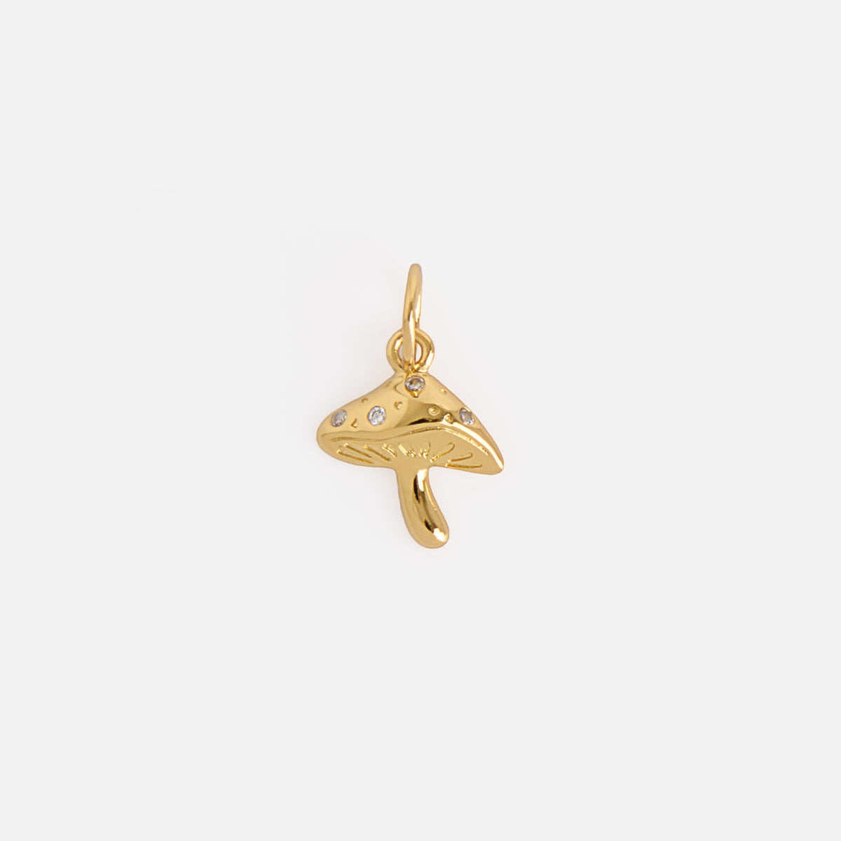 The Charms by Mod and Jo features a small gold mushroom-shaped charm with a top loop and several tiny gemstone accents, shown on a plain white background.