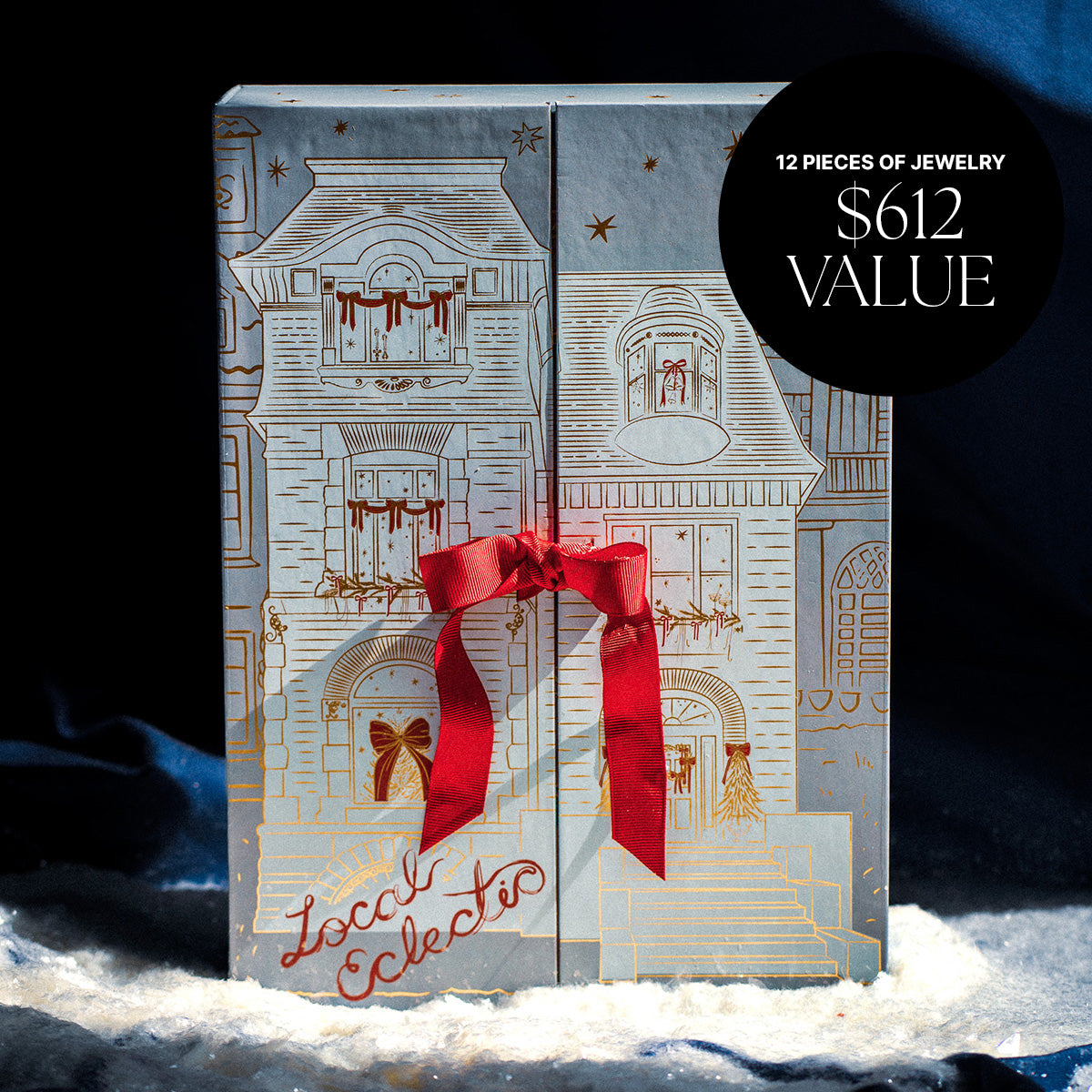 The 2025 Jewelry Advent Calendar comes in a house-illustrated box with a red ribbon and snow accents. A black circle notes “12 pieces of jewelry, $612 value.” “Local Eclectic” appears in red script at the bottom.