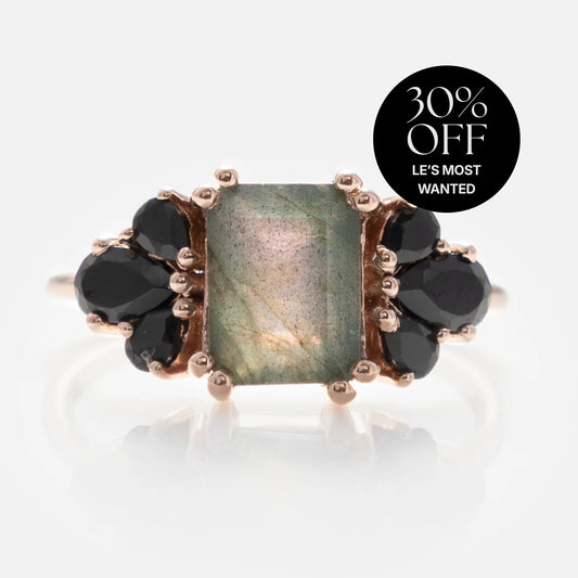 The Gemstone Empress Ring: a gold statement ring with a rectangular green gemstone, black stone clusters on each side, and a "30% OFF LES MOST WANTED" label in the background.