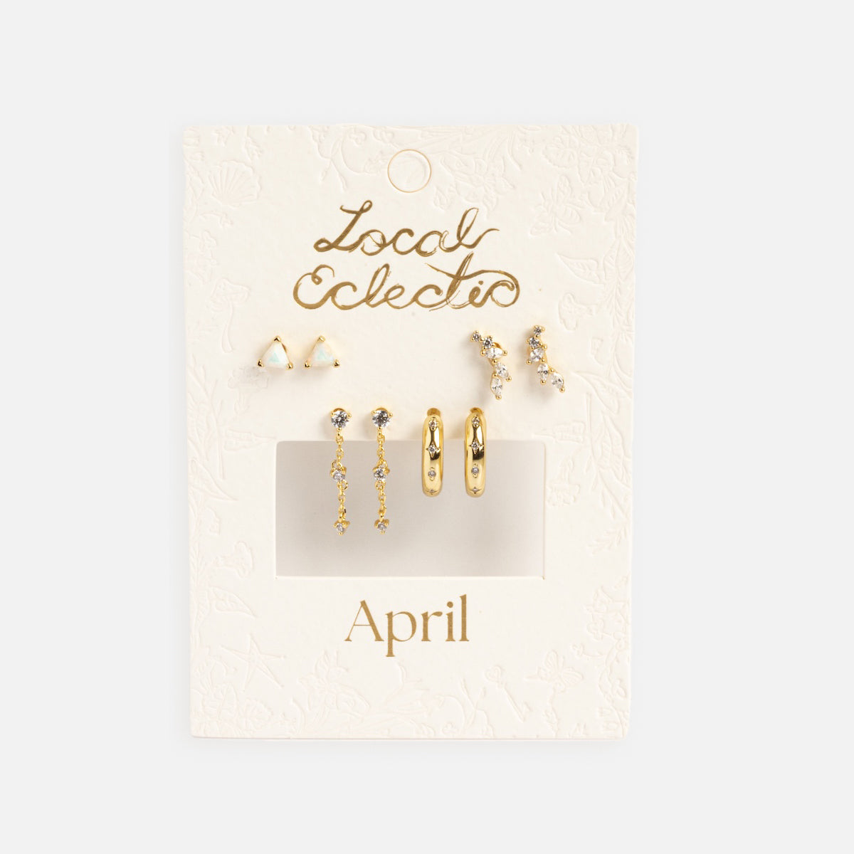 A display card labeled Classic Birthstone Earring Set features five pairs of 14k gold plated and crystal earrings—studs, hoops, and dangly styles—ideal for personalizing your ear stack against a textured off-white background.