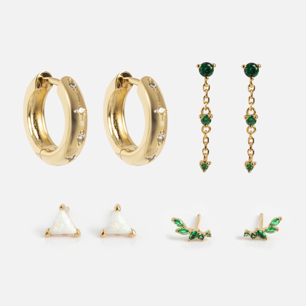 The Bold Birthstone Earring Set features five gold pairs: small hoops with crystals, dangling green gemstone earrings, triangular opal studs, and two green leaf-themed stud styles, all displayed on a light background.