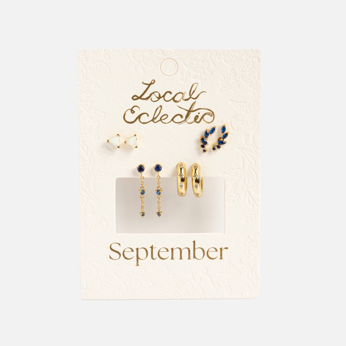 The Classic Birthstone Earring Set features five 14k gold plated earrings in gold and blue—studs, hoops, and drops—displayed on a cream card labeled Local Eclectic and September, ideal for creating your own personalized ear stack.