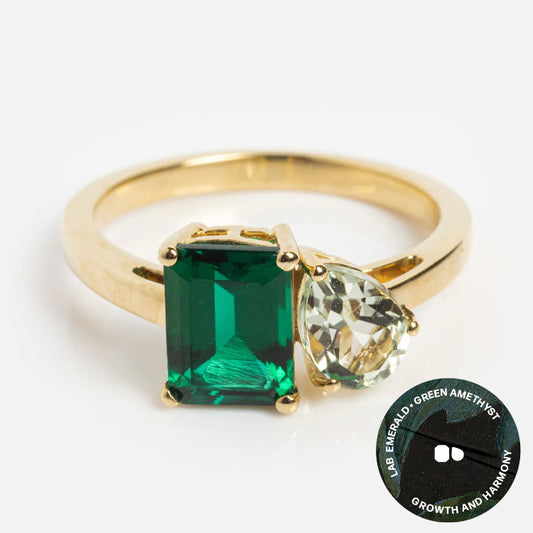 The Solid Gold Toi et Moi Colorful Gemstone Ring features a rectangular lab emerald and a pear-shaped green amethyst, symbolizing growth and harmony with gemstone icons.