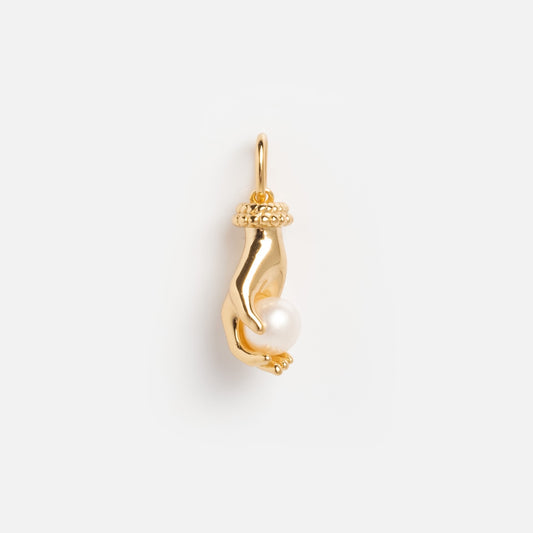 The Vintage Inspired Trinket Charm is a gold hand-shaped pendant holding a round white pearl, featuring a top loop for attaching to a chain, shown against a plain white background.