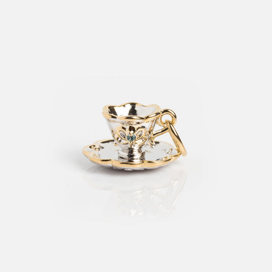 The Vintage Inspired Trinket Charm is a small gold vermeil teacup with a matching saucer, decorative details, and a loop for attaching to a bracelet or necklace, shown on a white background.