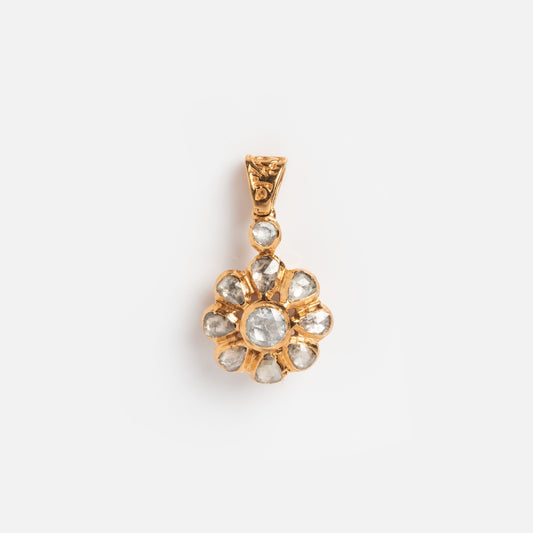 The Vintage 14k Rose Cut Diamond Floral Cluster Charm features a gold floral design with a central round clear stone, surrounded by smaller clear stones in petal-shaped settings, evoking classic vintage diamond charm elegance.