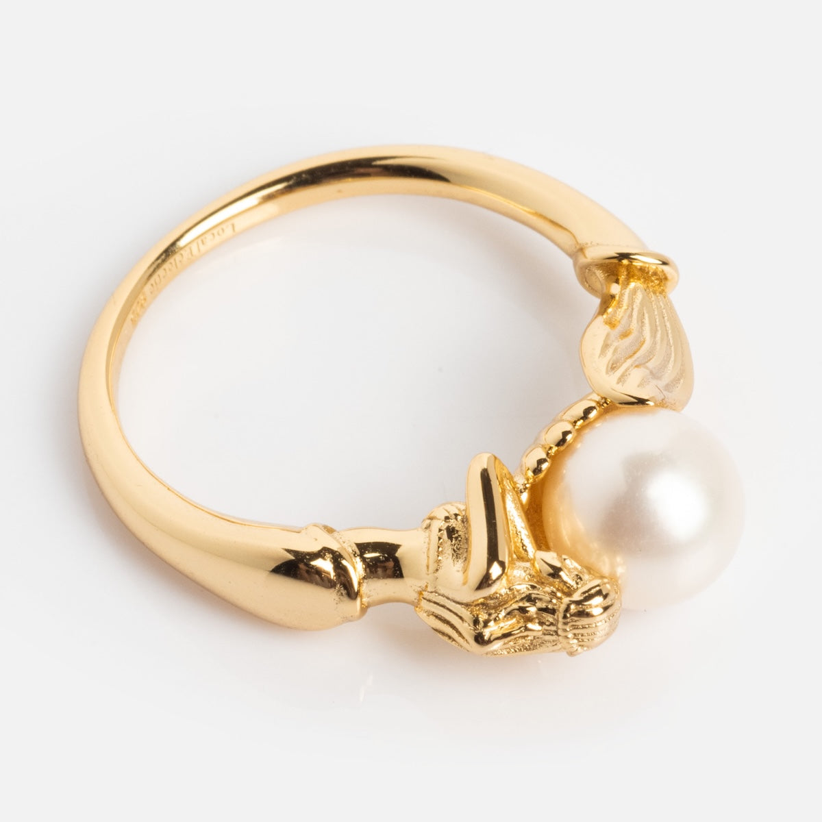The Pearl Siren Statement Ring features a sculpted lion’s head gripping a large round white pearl, with intricate band details—creating a bold, vintage-inspired gold ring against a plain white background.