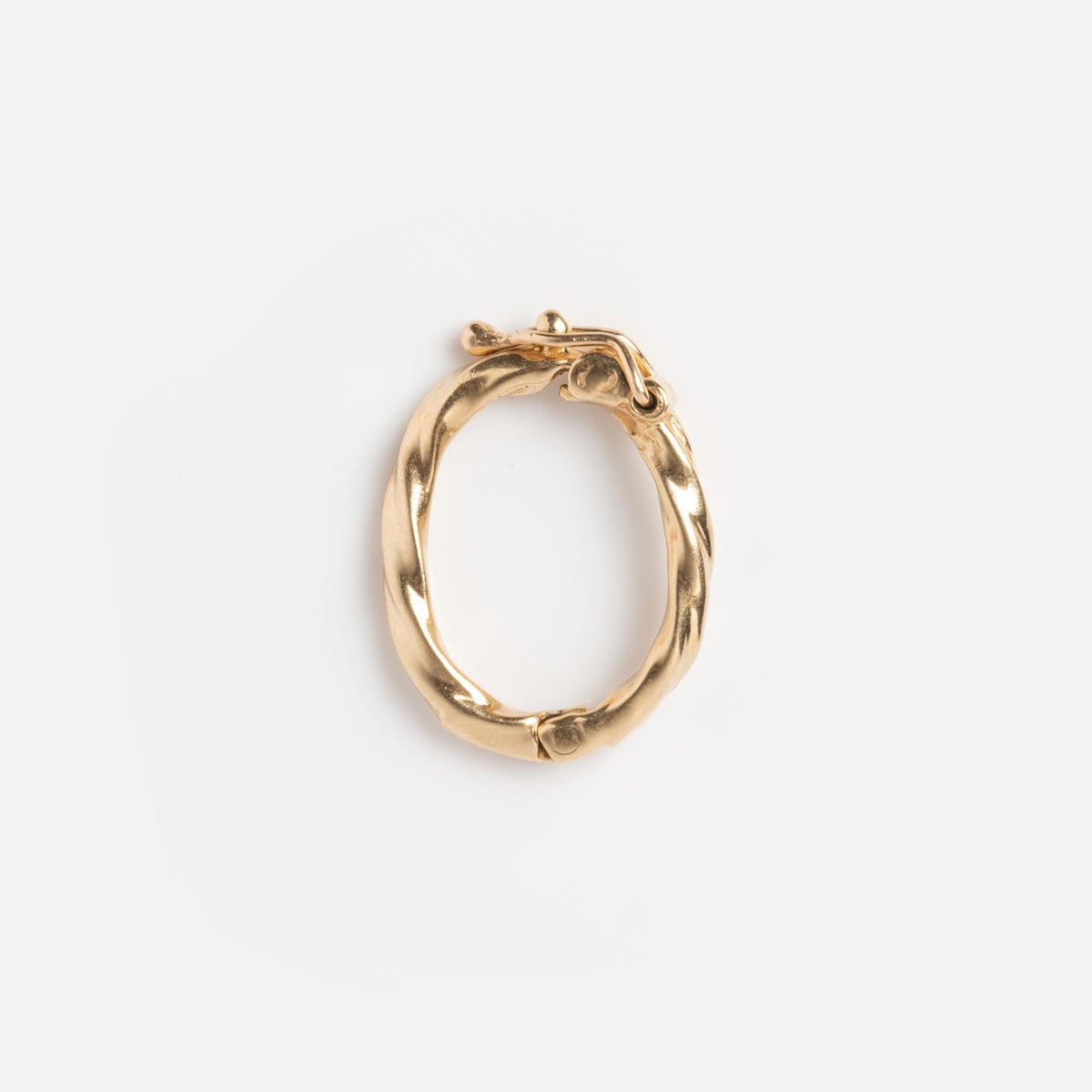 The Vintage 14k Textured Charm Clip features a single gold hoop earring with a twisted, textured design, evoking vintage elegance and displayed against a plain white background.