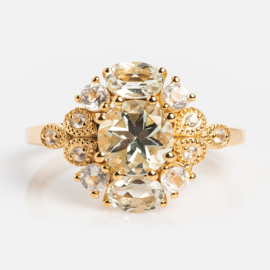 The Royal Gardens Green Amethyst Cocktail Ring showcases a large oval green amethyst center, accented by smaller stones and detailed 14k Gold Vermeil, set against a plain white background.