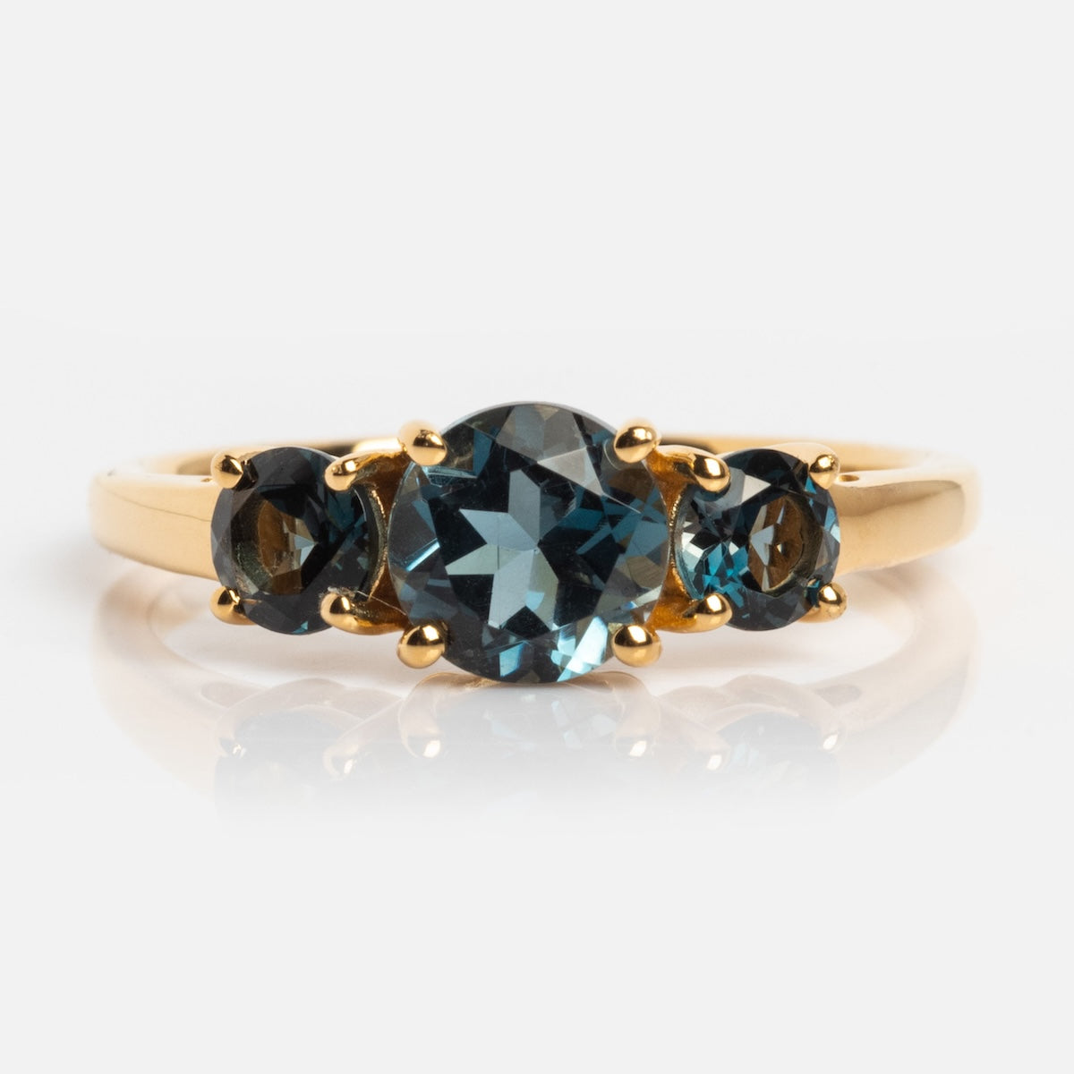 The London Blue Topaz Trilogy Ring features a vintage-inspired gold design with an oval-cut center stone and two smaller round gems, all set against a plain white background.