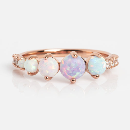The Pastel Opal Shooting Star Ring features five round opals of varying sizes, the largest at the center, set in rose gold vermeil with small white accent stones along the band for celestial charm.