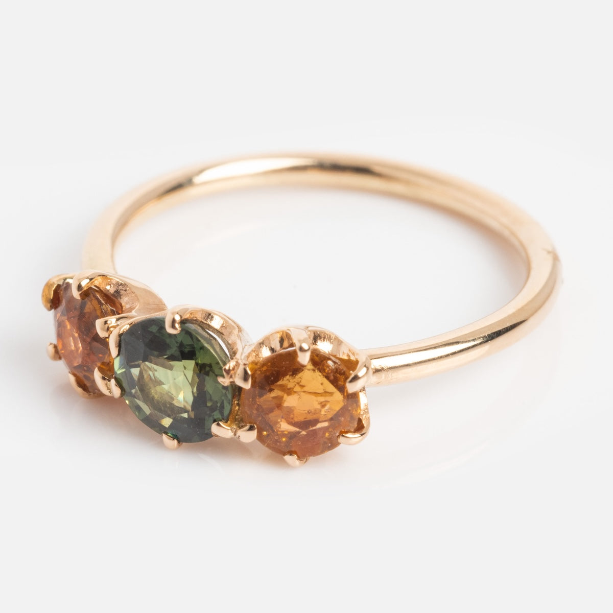 The Vintage 14k 1900s Tourmaline Trio Ring Size 4.5 features a green center tourmaline flanked by two orange stones, each round and prong-set in yellow gold, displayed on a plain white background.