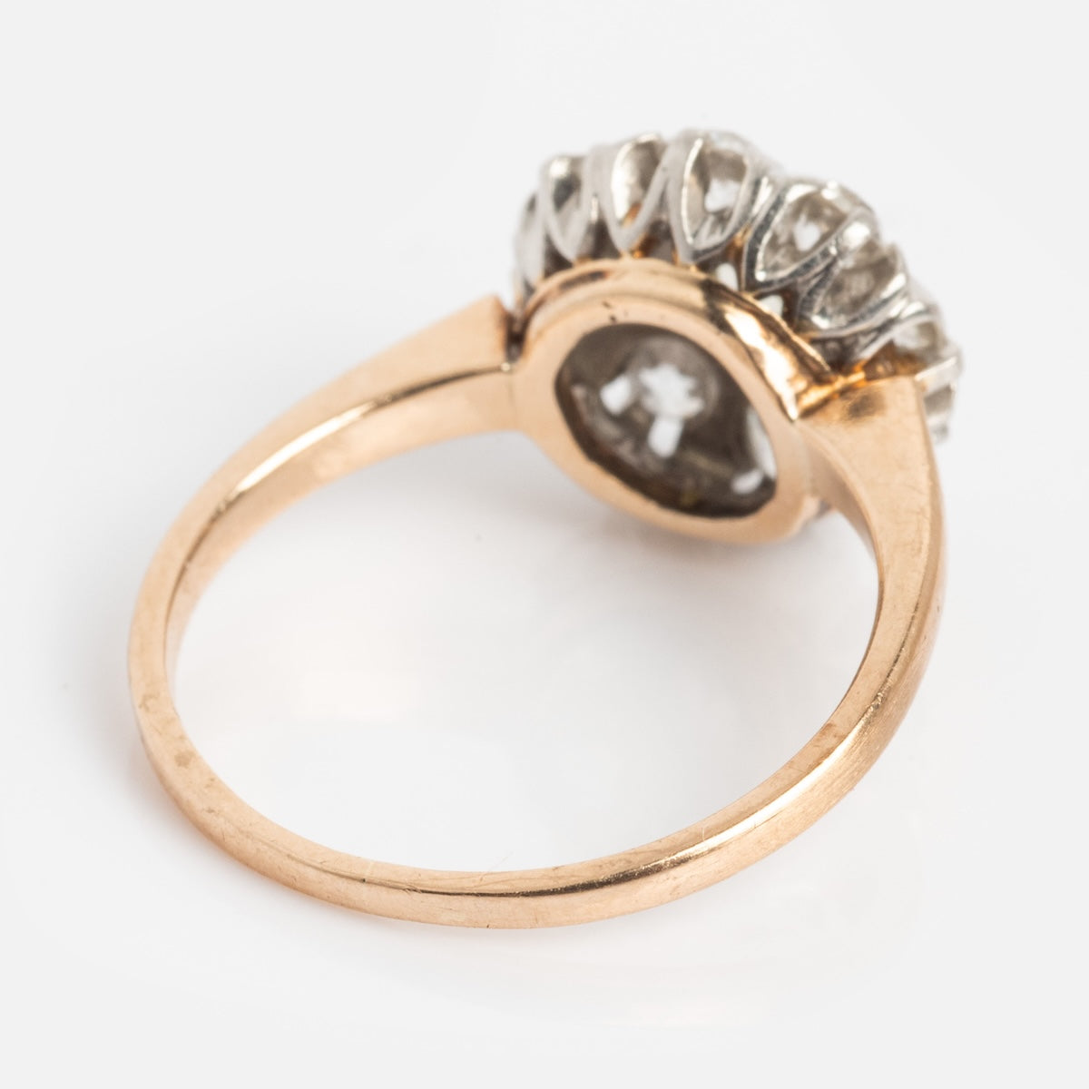A Vintage 14k 1920s Euro Cut Diamond Cluster Ring, size 5, in yellow gold with a split shank and raised oval cluster of clear diamonds, shown from the side against a white background.