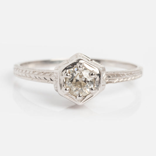 The Vintage 18k White Gold Hexagon Set Diamond Ring, size 7, features a round diamond in a hexagonal setting and detailed engraving on the band.