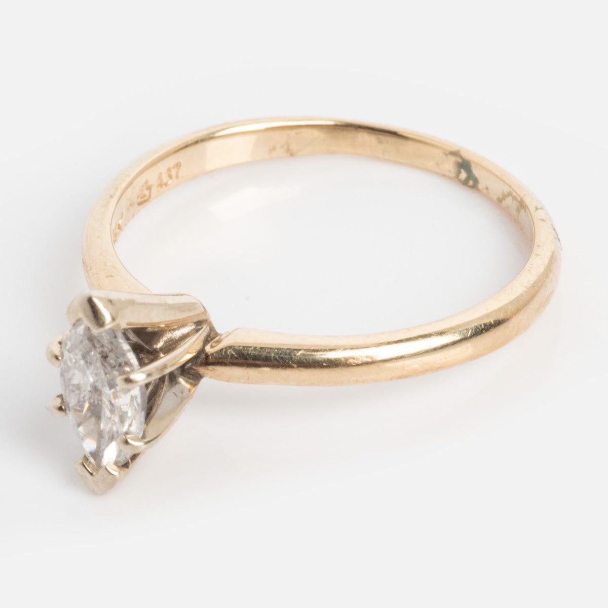 A vintage 14k gold engagement ring from the 1960s, featuring a marquise solitaire diamond in size 7, displayed on a light background.