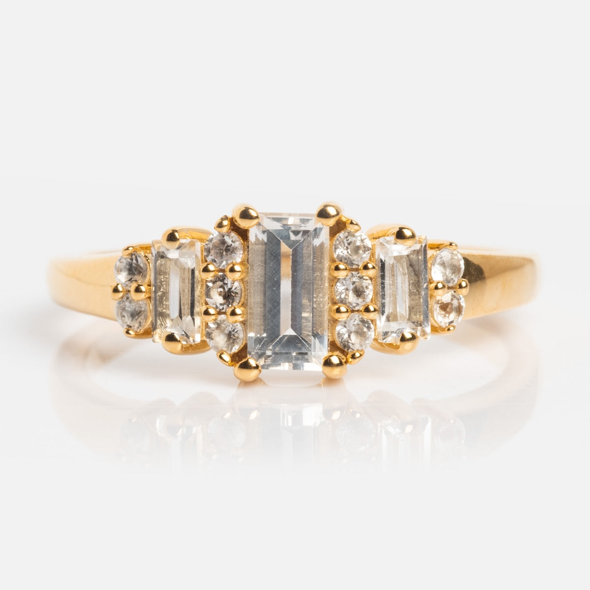 The Third Act Art Deco Ring showcases a rectangular center stone flanked by two smaller gems and clusters of round diamonds, all set on a polished 14k gold vermeil band with vintage-inspired design.