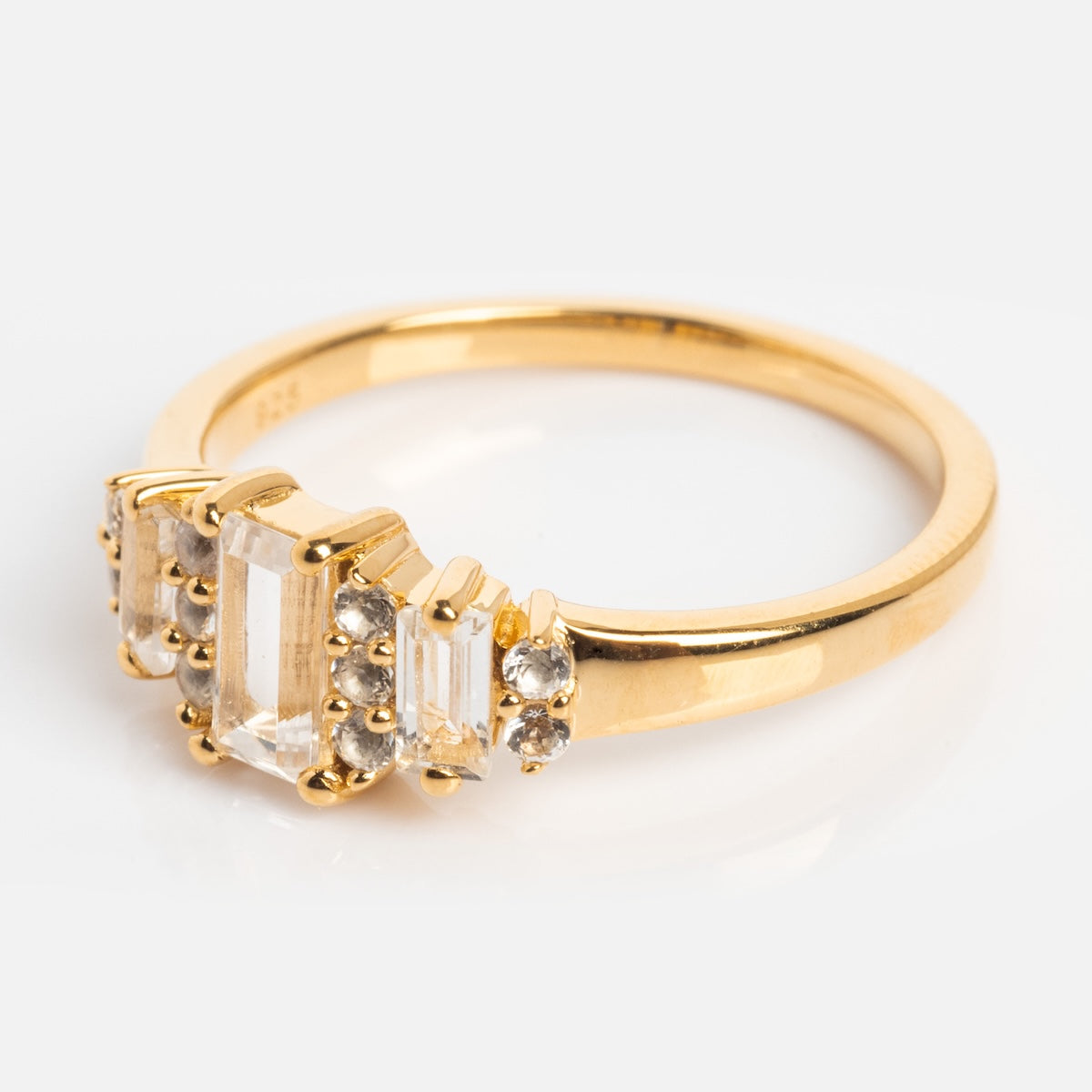 The Third Act Art Deco Ring features a vintage-inspired 14k gold vermeil band with a rectangular clear center stone, accented by smaller clear stones on each side, all set against a plain white background.