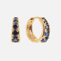 The Sapphire Soliloquy Huggie Hoops are vintage-inspired 14k gold vermeil earrings, each set with five round blue gemstones along the front outer edge, shown against a plain white background.