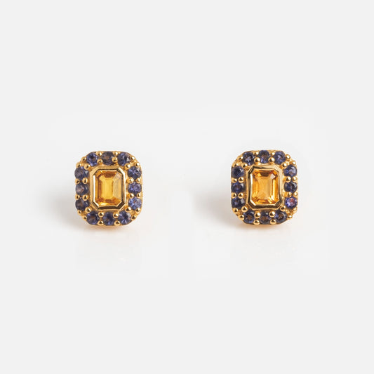 The Citrine and Iolite Novella Studs feature gold vermeil rectangular studs with a central yellow citrine gemstone, surrounded by small blue iolite stones—an elegant accessory for any occasion.
