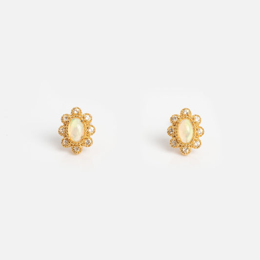 The Opal Majesty Studs are vintage-inspired gold earrings with oval Ethiopian opals at the center, encircled by a floral halo of small round gems. Shown on a plain white background.