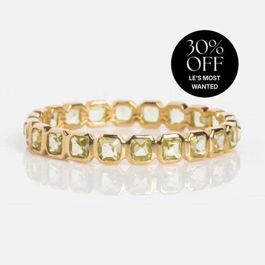 A Solid Gold Gemstone Eternity Stacking Ring set with square light green gemstones is shown on a white background. A black circle in the corner says 30% OFF LES MOST WANTED—this peridot ring is a true eternity band.