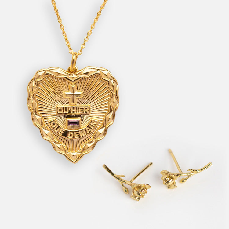 The Valentines Day Hearts and Flowers Gift Set includes a gold heart pendant necklace engraved with QUHIER QUE DEMAIN and two gems, paired with delicate birth flower earrings—an elegant set displayed on a white background.