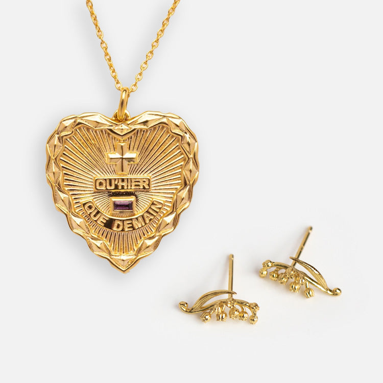 The Valentines Day Hearts and Flowers Gift Set features a gold heart pendant engraved with QUHIER and QUE DEMAIN, paired with delicate birth flower earrings, creating a timeless jewelry ensemble on a white background.