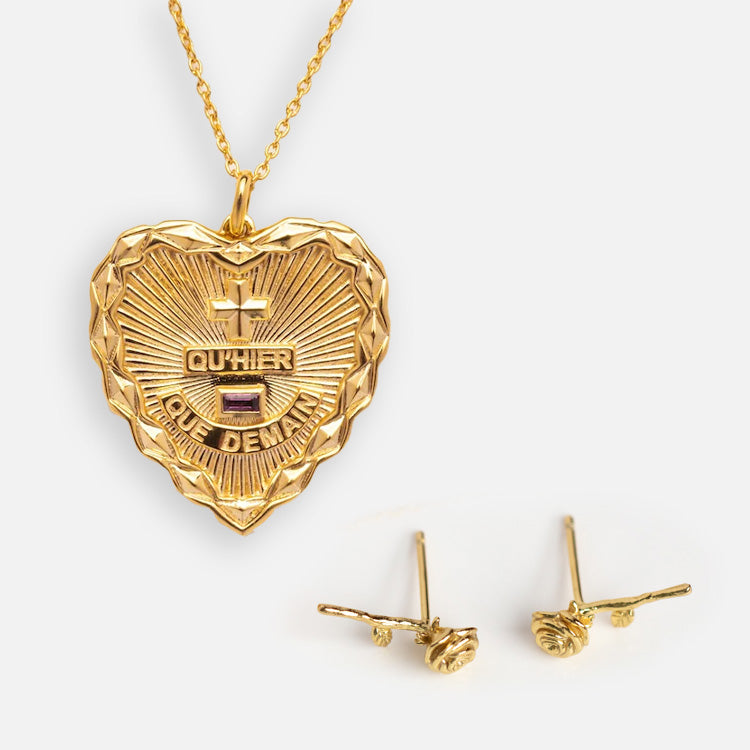 The Valentines Day Hearts and Flowers Gift Set features a gold heart pendant necklace engraved with QUHIER QUE DEMAIN and two gemstones, plus matching gold stud earrings—an elegant choice for celebrating love.
