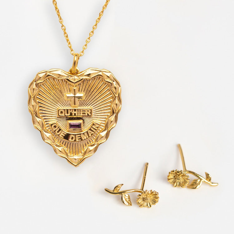 The Valentines Day Hearts and Flowers Gift Set features a gold heart pendant engraved with QUHIER QUE DEMAIN and gold daisy birth flower earrings, beautifully displayed on a white background.