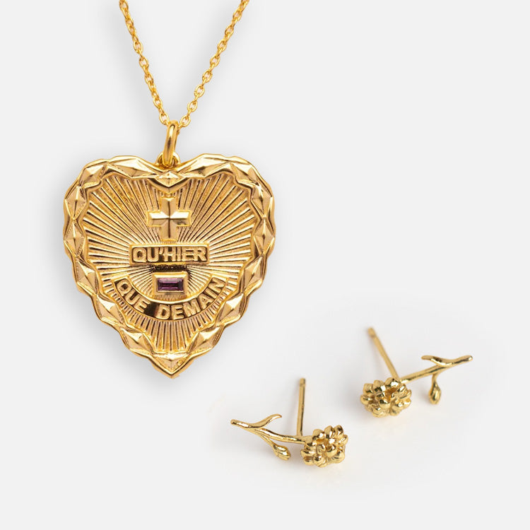 The Valentines Day Hearts and Flowers Gift Set features a gold heart pendant necklace engraved with QUHIER QUE DEMAIN and two gemstones, paired with small birth flower earrings, all shown on a white background—ideal for jewelry lovers.