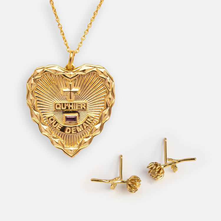 The Valentines Day Hearts and Flowers Gift Set features a gold heart pendant engraved with QUHIER QUE DEMAIN and two gemstones, paired with gold birth flower earrings, shown together on a white background.