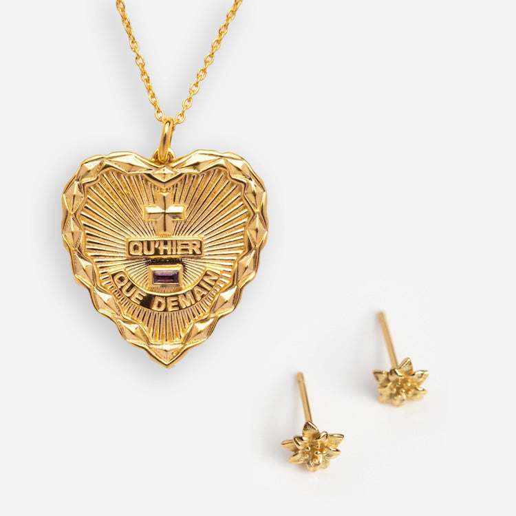 The Valentines Day Hearts and Flowers Gift Set features a gold sunburst heart pendant engraved with QUHIER QUE DEMAIN and two star-shaped gold stud earrings, elegantly displayed on a white background.