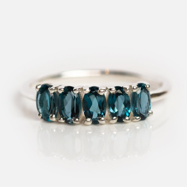 The London Blue Topaz Galaxy Ring in Silver features five oval-cut, deep blue gemstones set in a sterling silver band, shown against a plain white background.
