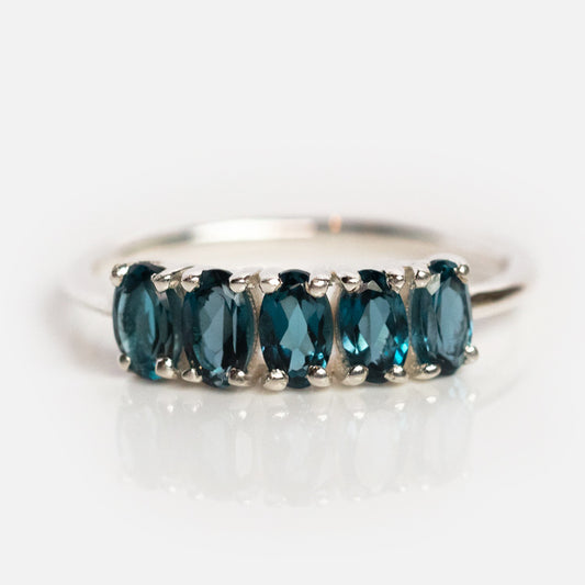 The London Blue Topaz Galaxy Ring in Silver features five oval-cut, deep blue gemstones set in a sterling silver band, shown against a plain white background.