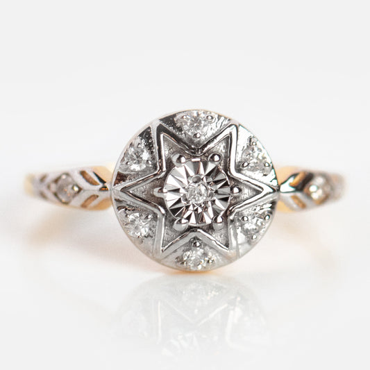 The Vintage Star Compass Ring features a round, star-shaped setting with a central diamond, smaller diamonds, detailed band engraving, and is crafted in sterling silver with 14k yellow gold plating.