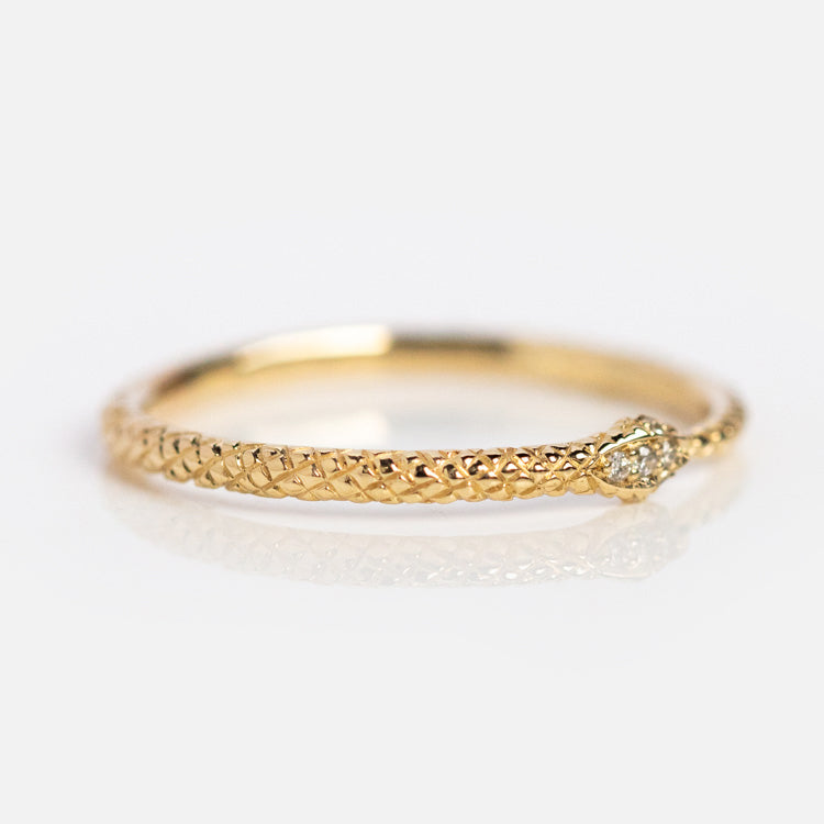 The Ouroboros Diamond Snake Ring in 14k solid gold features a textured braided band and a small round diamond accent on one side, shown on a white surface.