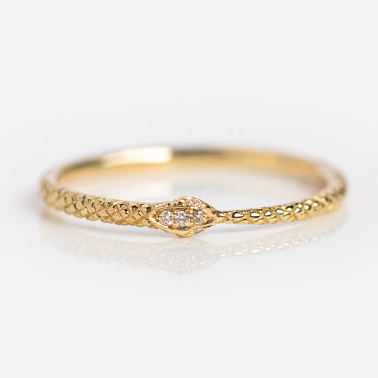 The Ouroboros Diamond Snake Ring features a delicate 14k solid gold, snake-like textured band and a pointed head set with tiny diamonds, beautifully photographed on a light background.
